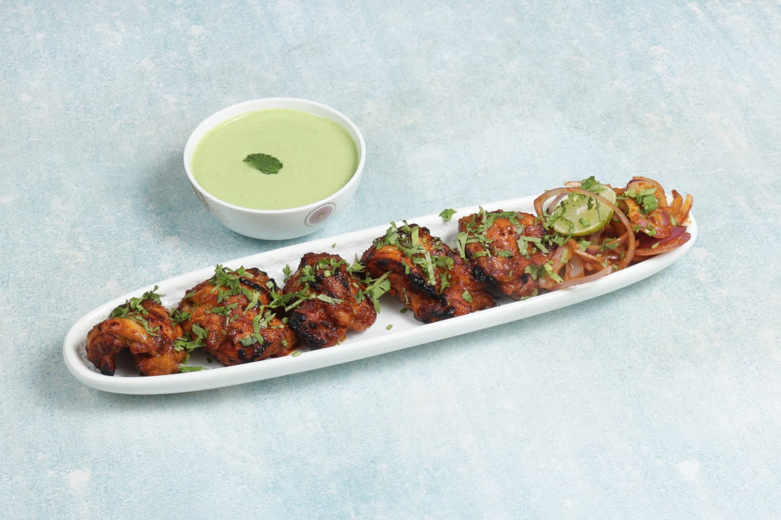 Grilled chicken tikka skewers with onion and lime